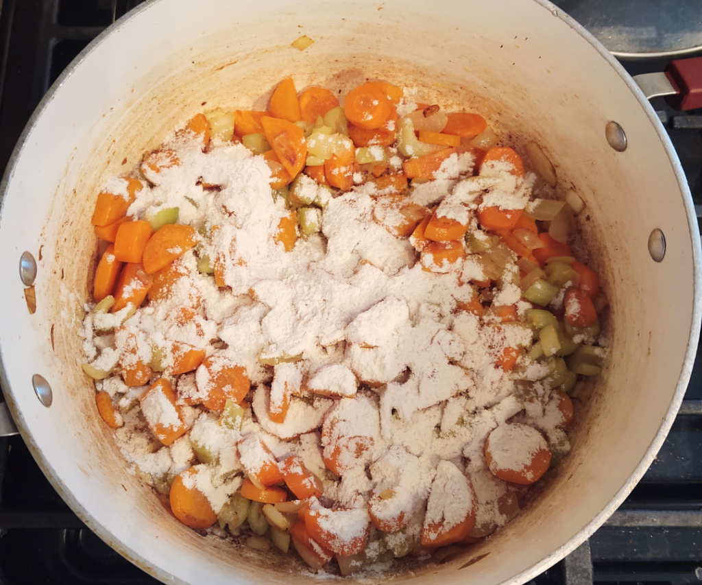 Adding flour to vegetables to make roux