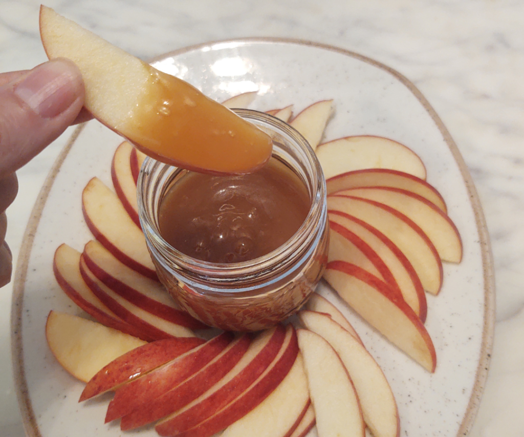 dipping apple in caramel sauce made with honey